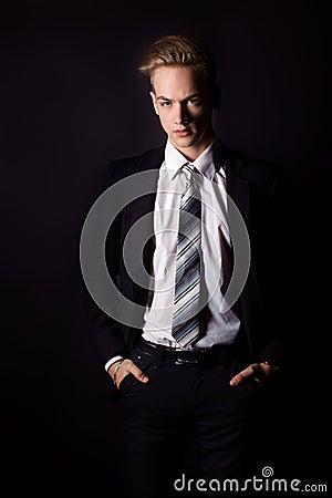 Young handsome man in a business suit and a white shirt and tie in formal style in the Studio on a black background Stock Photo