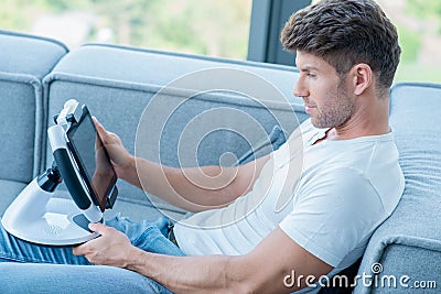 Young Handsome Man on Couch Playing His Gadget Stock Photo