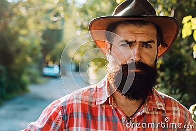 Young handsome man in cowboy hat with long beard, mustache and trendy hairdo. Stock Photo