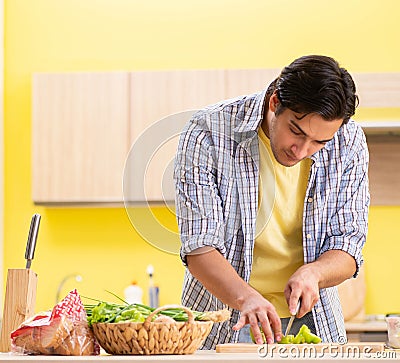 Young handsome man cutting pepper in the kitchen Stock Photo