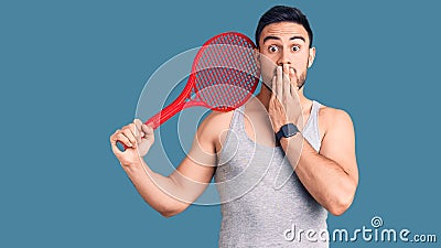 Young handsome man holding tennis racket covering mouth with hand, shocked and afraid for mistake Stock Photo
