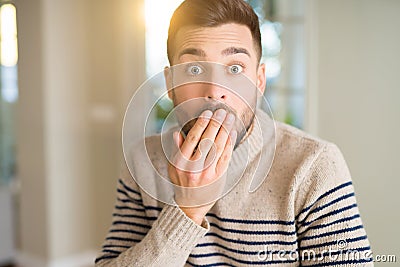 Young handsome man at home cover mouth with hand shocked with shame for mistake, expression of fear, scared in silence, secret Stock Photo