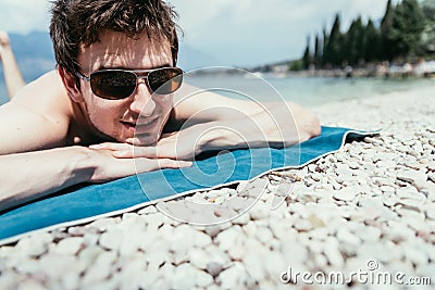 Young handsome man is lying on the beach, sun glasses Editorial Stock Photo