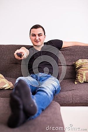 Young handsome man watching TV on a sofa at home Stock Photo