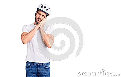 Young handsome man wearing bike helmet sleeping tired dreaming and posing with hands together while smiling with closed eyes Stock Photo