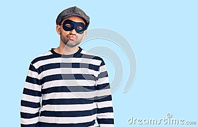 Young handsome man wearing burglar mask looking at the camera blowing a kiss on air being lovely and sexy Stock Photo