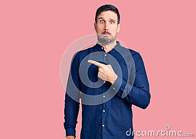 Young handsome man wearing casual shirt pointing aside worried and nervous with forefinger, concerned and surprised expression Stock Photo