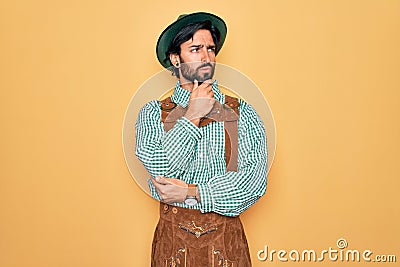 Young handsome man wearing tratidional german octoberfest custome for Germany festival with hand on chin thinking about question, Stock Photo