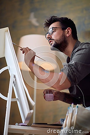 Young handsome painter working on details of the painting Stock Photo