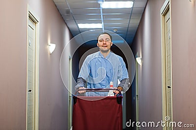 Young handsome pushing cleaning cart - a series of HOTEL images. Stock Photo