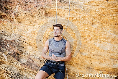 Young handsome sportsman getting ready to climb a cliff Stock Photo