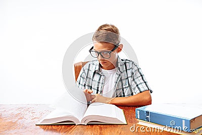 Young handsome teen guy reading book sitting at table, schoolboy or student doing homework, in Studio Stock Photo