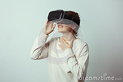 Young handsome woman wearing virtual headset. Excited Hipster using VR glasses. Empty studio wall background Stock Photo