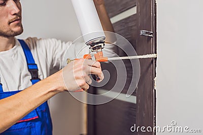 Young handyman installing door with an mounting foam in a room Stock Photo