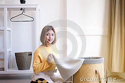 Young happy asian woman doing laundry with basket at home Stock Photo