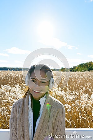 Young happy Asian woman smiling against scenic view of autumn bulrush field Stock Photo