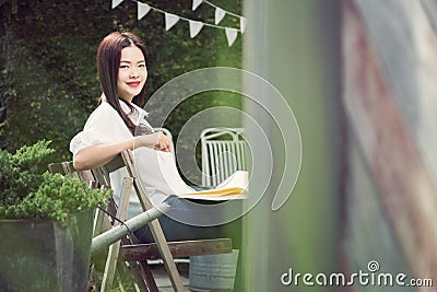 Young happy asian woman smiling at camera holding a book Stock Photo