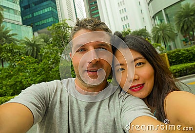 Young happy and attractive mixed Asian Caucasian ethnicity couple in love taking selfie picture together smiling cheerful enjoying Stock Photo