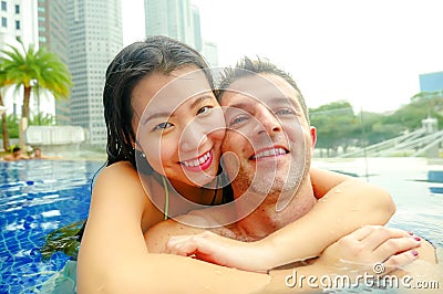 Young happy and attractive playful couple taking selfie picture together with mobile phone at luxury urban hotel infinity pool enj Stock Photo