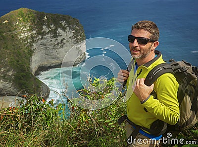 Young happy and attractive sporty hiker man with trekking backpack hiking at sea cliff landscape feeling free enjoying travel Stock Photo