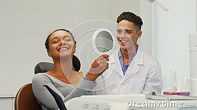 Beautiful woman checking her smile in the mirror at the dental clinic Stock Photo