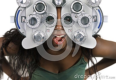 Young and happy black afro American woman at hospital looking through optometric hospital device checking eyes having sight exam Stock Photo