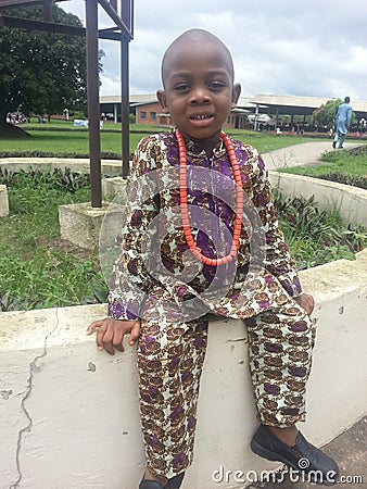 Happy young brother wearing traditional print attire with beads seats at an open Ota Assembly of the Jehovahs Witnesses in Nigeria Editorial Stock Photo