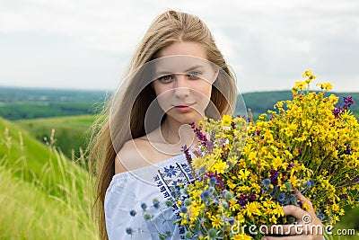 Young happy bride holding bouquet of blooming yellow flowers in countryside. Picture of beautiful happy girl with long light hair Stock Photo