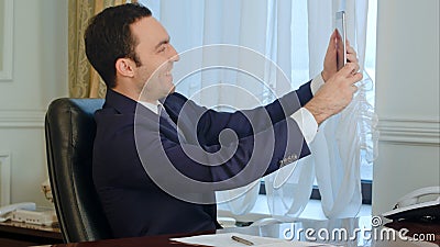 Young happy businessman man taking funny selfies with digital tablet in the office Stock Photo