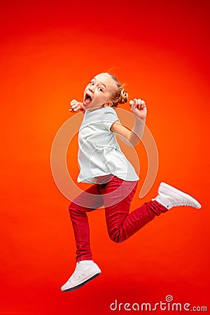 Young happy caucasian teen girl jumping in the air, isolated on red studio background. Stock Photo