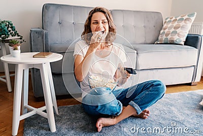 Young happy cheerful fuuny woman watchingTV, movies and eating popcorn, spending time at home Stock Photo
