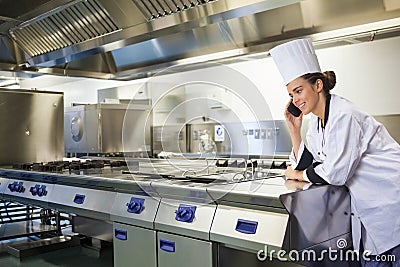 Young happy chef standing next to work surface phoning Stock Photo