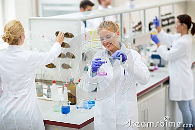 Young happy chemical technician pour fluid in a chemical flask Stock Photo