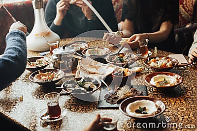 Young happy company of people is eating lebanon food and smokinh shisha. Lebanon cuisine. Stock Photo