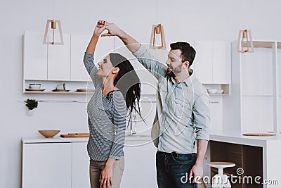 Young Happy Couple Dancing in Modern Kitchen. Stock Photo