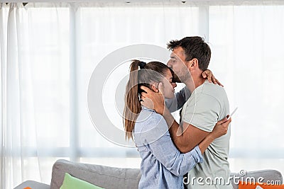 Young happy couple hugging and kissing after they realize that they will have a baby. Pregnant woman hugging her man Stock Photo