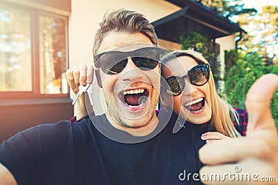 Young happy couple with keys in hand standing outside of their new home Stock Photo