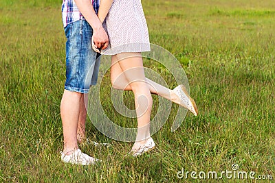 Young happy couple kissing in love, standing on the grass in the summer sun the night Stock Photo