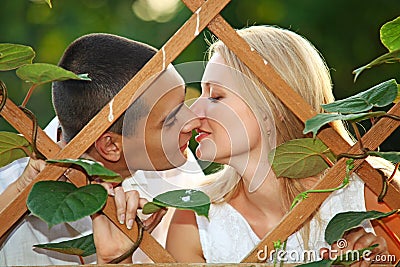 Young happy couple kissing at wooden lattice Stock Photo