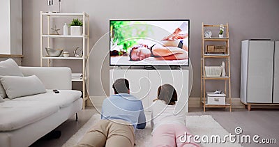 Young Happy Couple Lying On Carpet Watching Movie On Television Stock Photo