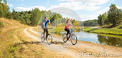 Young Happy Couple Riding Bicycles by the River Stock Photo