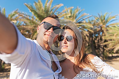 Young happy couple taking selfie on a palm beach . Summer vacations concept Stock Photo