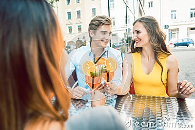 Happy couple toasting with their mutual female friend at a trendy restaurant Stock Photo