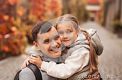 Young happy dad and little daughter hugging in autumn park. Family time, togehterness, parenting and happy childhood concept. Stock Photo