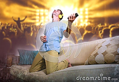 Young happy and excited man jumping on sofa couch listening to m Stock Photo