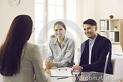 Young smiling family couple meeting with bank worker to sign loan contract Stock Photo