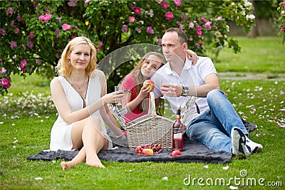 Young happy family having picnic outdoors Stock Photo