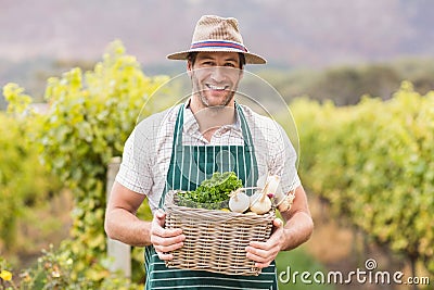 Young happy farmer holding a basket of vegetables Stock Photo