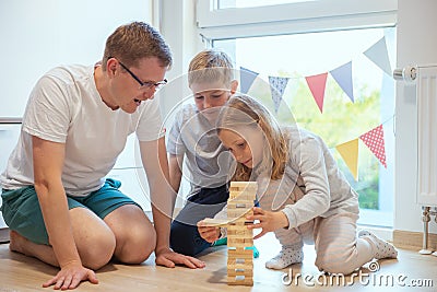 Young happy father playing with his two cute children with wooden blocks Stock Photo