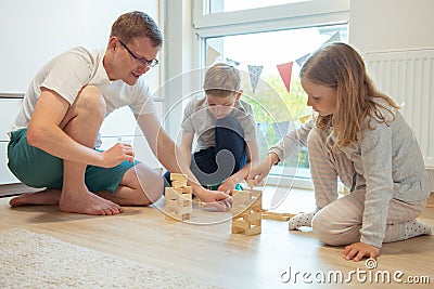 Young happy father playing with his two cute children with wooden blocks Stock Photo